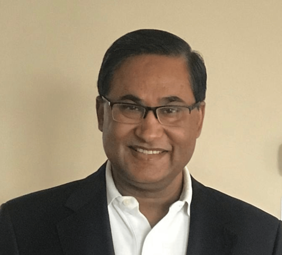 a man wearing a suit and tie smiling at the camera